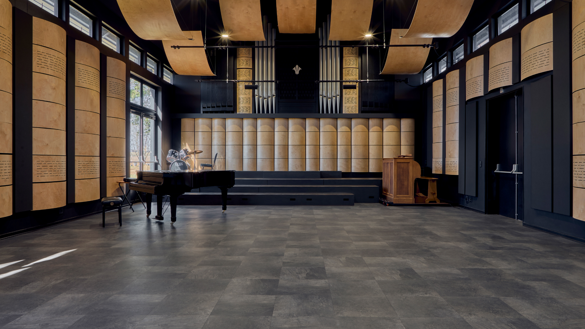Performance hall with dark stone-look flooring and wooden acoustic panels